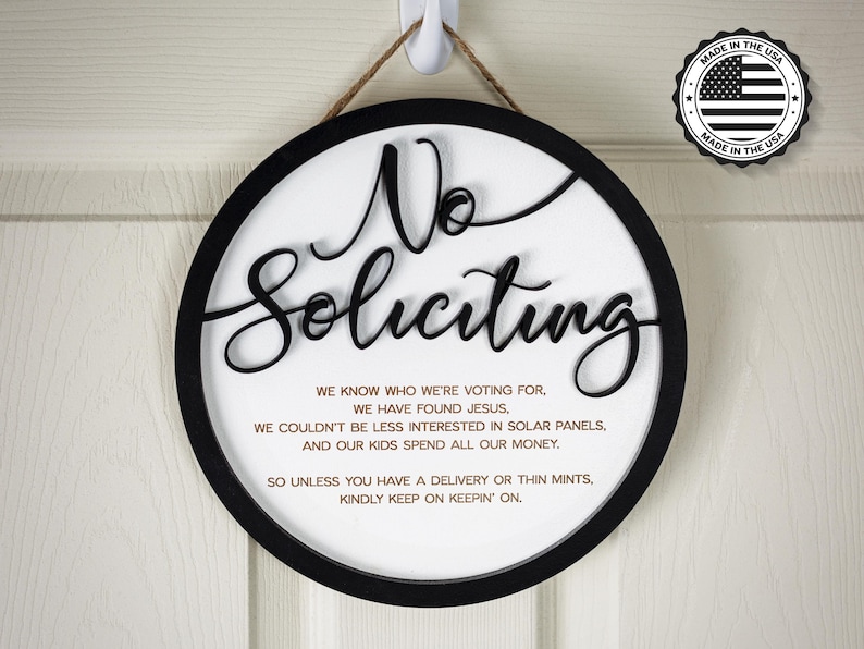 May include: A round, black and white sign with the text "No Soliciting" in large, black, cursive letters. The sign also includes a message explaining why the residents do not want to be solicited.