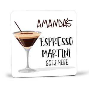 May include: Square white coaster with a graphic of an espresso martini. The coaster has the text "AMANDA'S ESPRESSO MARTINI GOES HERE" in black and brown lettering. A cocktail glass with a brown drink and a straw is on the left.