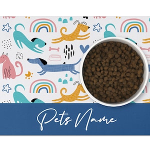 May include: White pet bowl with brown kibble on a white and blue dog-themed placemat with the text "Pets Name" on the bottom.