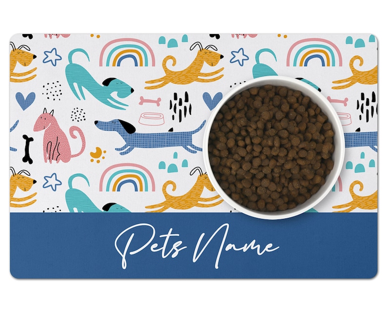 May include: White pet bowl with brown kibble on a white and blue dog-themed placemat with the text "Pets Name" on the bottom.