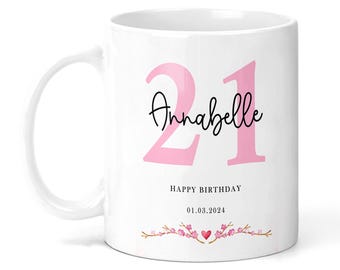 May include: White ceramic mug with a pink 21 and the name Annabelle in black script. The text "Happy Birthday" and the date "01.03.2024" are printed below the name. A pink heart and a floral design are at the bottom of the mug.