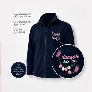Könnte beinhalten: Eine marineblaue Fleecejacke mit durchgehendem Frontreißverschluss und Stehkragen. Auf der Brust befindet sich ein gesticktes Motiv mit dem Text "Hannah" und "Job Role", umgeben von rosa und weißen Blumen sowie zwei violetten Schmetterlingen.