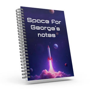 May include: A spiral bound notebook with a space-themed cover. The cover features a rocket ship flying through a purple and blue galaxy with stars and planets. The text on the cover reads "Space For George's notes".