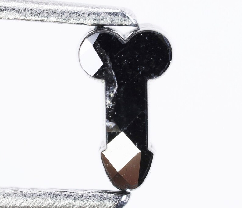 May include: A black diamond shaped like a key with a faceted design.