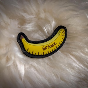 Op de afbeelding: Een gele bananenpatch met een zwarte omtrek en de tekst "For Scale" erop gedrukt.