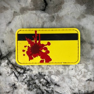 May include: Yellow and black rectangular patch with a red blood splatter design.