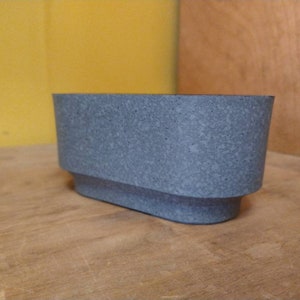 May include: A gray concrete planter with a rectangular shape and a slightly rounded top.
