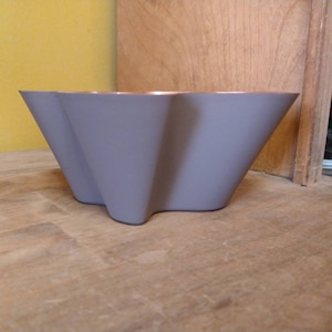 May include: A gray, star-shaped cake pan with a fluted edge. The pan is made of metal and has a non-stick coating.