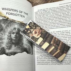 May include: A bookmark with a gold tassel, featuring a vintage illustration of a woman and the text "WHISPERS OF THE FORGOTTEN." The bookmark has a floral and book design.