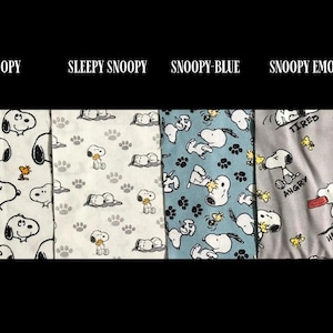 May include: Four fabric patterns featuring Snoopy. The first pattern is white with Snoopy and Woodstock. The second is white with Snoopy paw prints. The third is blue with Snoopy. The fourth is grey with Snoopy and the words "Tired", "Angry", and "Hungry".