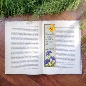 May include: A counted cross stitch pattern for a bookmark featuring a yellow butterfly, blue flowers, and the text "Your word is a lamp for my feet, a light on my path. Psalm 119:105".