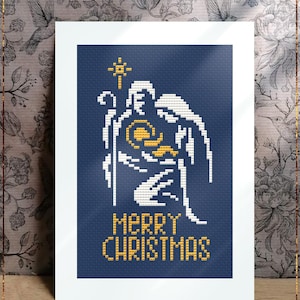 Può includere: Un modello a punto croce contato incorniciato con sfondo blu. Il disegno presenta un angelo bianco che tiene un bastone e un'aureola dorata. Le parole "MERRY CHRISTMAS" sono in oro. Il testo "Christmas Family" e "Counted cross stitch pattern" sono in basso.