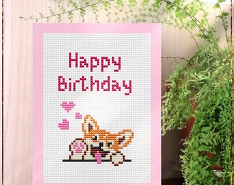 Può includere: Un biglietto rosa con le parole "Buon compleanno" in lettere rosse. Un cane di cartone animato con pelliccia marrone, arancione e bianca sta guardando da sopra la parte superiore del biglietto. Il cane tiene un cuore rosa in bocca e ci sono tre cuori rosa che galleggiano sopra il cane. Il biglietto ha le parole "Birthday Dog" e "Counted cross stitch pattern" stampate sotto l'immagine.