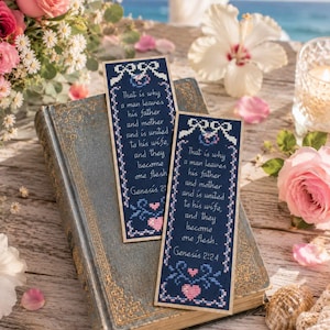 Puede incluir: Dos marcapáginas de punto de cruz azul marino con el texto "That is why a man leaves his father and mother and is united to his wife, and they become one flesh. Genesis 2:24." Los marcapáginas descansan sobre un libro antiguo, rodeados de flores.
