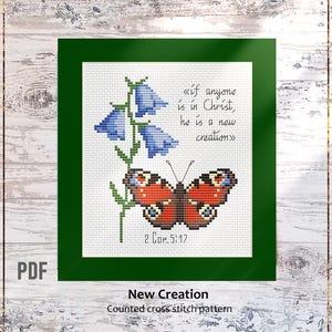 Puede incluir: Patrón de punto de cruz con una mariposa y flores de campanillas azules. La mariposa tiene detalles rojos, marrones y azules. El texto incluye "si alguno está en Cristo, nueva criatura es" y "2 Cor 5:17".