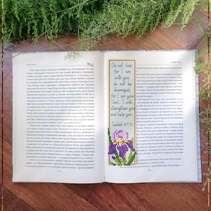 May include: Open book with a bookmark featuring a cross-stitch design of an iris and text from Isaiah 41:10. The bookmark reads "Do not fear, for I am with you; do not be dismayed, for I am your God. I will strengthen you and help you."