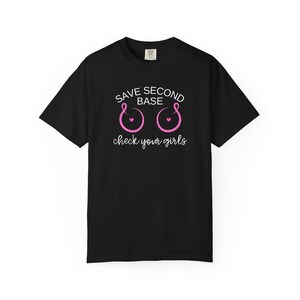 May include: A black short-sleeve t-shirt featuring the white text SAVE SECOND BASE and check your girls, with two pink ribbon graphics shaped like circles, each containing a small pink heart in the center, centered on the chest area.