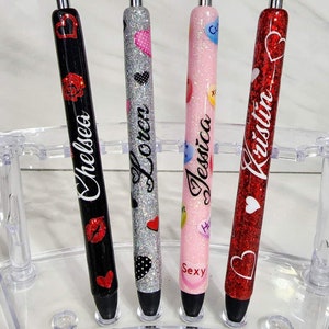 Puede incluir: Cuatro bol&iacute;grafos personalizados en un soporte transparente. Los bol&iacute;grafos son negros, plateados, rosas y rojos, con purpurina y dise&ntilde;os de corazones. Cada bol&iacute;grafo tiene un nombre: Chelsea, Loren, Jessica y Kristin.