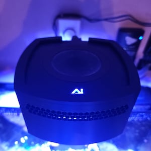 May include: A black aquarium light with a honeycomb pattern and a blue light emitting from the front. The light has a white logo that says "AI" on the front.
