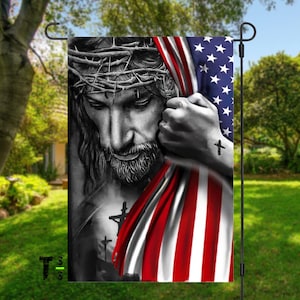 May include: A black and white image of Jesus Christ with a crown of thorns, holding an American flag. The flag is red, white, and blue with stars on the blue field. The image is a garden flag.