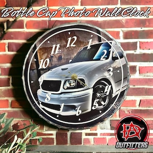May include: A white Ford F-150 pickup truck is featured on a round wall clock with black numbers and a black background. The clock is made from a bottle cap and has a silver rim. The text "Bottle Cap Photo Wall Clock" is at the top of the clock.