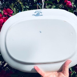 May include: White oval serving platter with blue floral accents and text. The platter has a slightly raised edge and a smooth surface. The text includes the word "England".