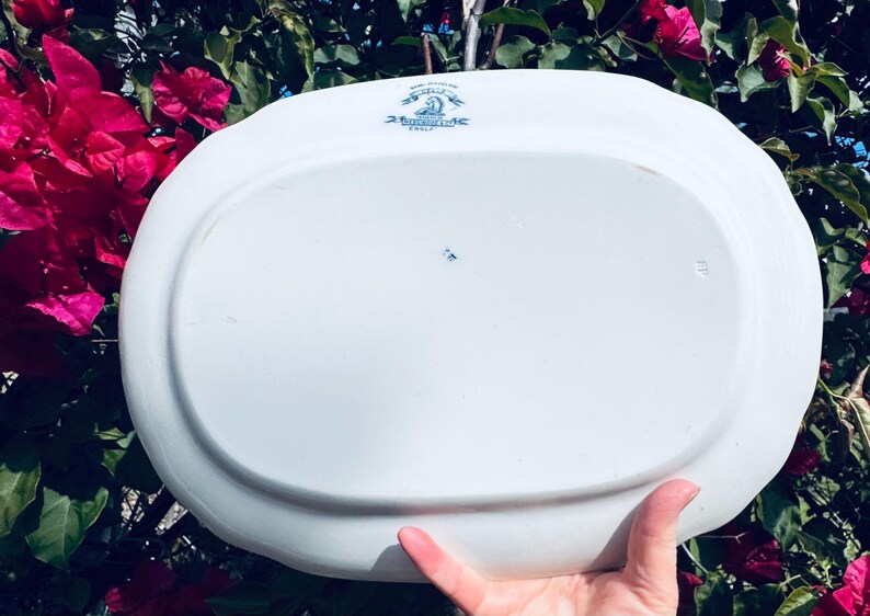 May include: White oval serving platter with blue floral accents and text. The platter has a slightly raised edge and a smooth surface. The text includes the word "England".