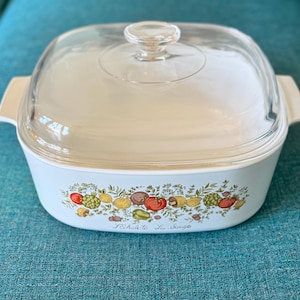 May include: A light blue square casserole dish with a clear glass lid. The dish features a colorful floral and vegetable design around the base, with the text "Léchate La Sauce".