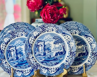 May include: A set of five blue and white ceramic plates with a floral pattern and a landscape scene. The plates are stacked on top of each other.