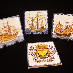 May include: Four decorative ceramic tiles with blue and white borders. Each tile features a hand-painted image of a ship with sails, a yellow and brown hull, and a blue ocean background. One tile features the text "LISBOA" in a banner.