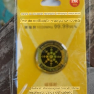 May include: A yellow and black round sticker with the text "Parche de protección radiológica de energía compuesta. Peta de codificación y aergia compuesta" and "Radiación electramagrana Dolor de cabeza, insomnio, caída del cabello Reduce eficazmente el dolor de cabeza, el malestar y la caída del cabello."
