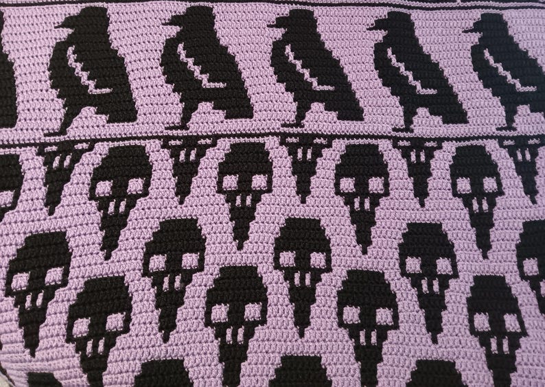 May include: A purple crocheted blanket with a repeating pattern of black ravens and skulls.