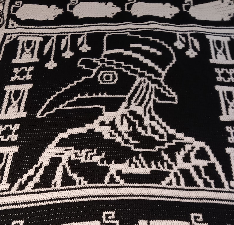 May include: Black and white crochet blanket with a pixelated design of a plague doctor. The blanket features a repeating pattern of Roman numerals.