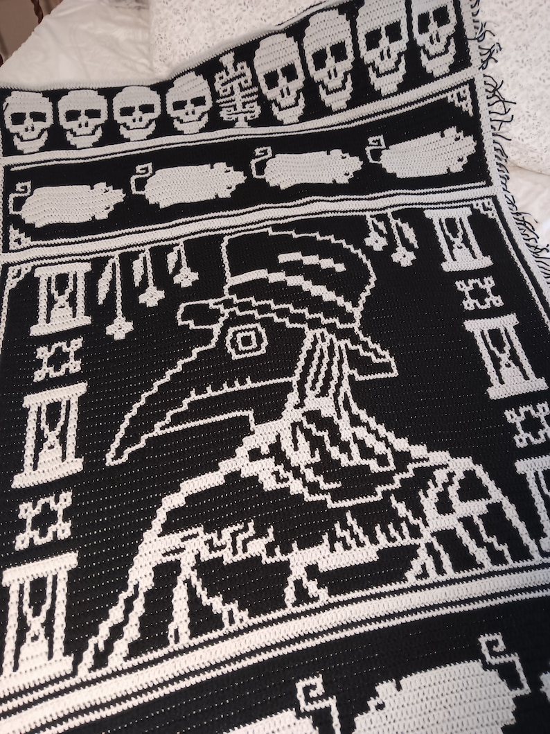 May include: Black and white crochet blanket with a skull and crossbones design. The blanket features a large, detailed image of a plague doctor with a long beak and a hat. The blanket is made with a thick, textured yarn.
