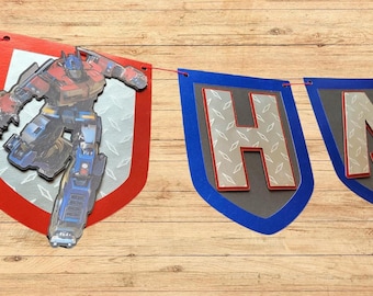 May include: A Transformers-themed birthday banner with the word "HAPPY" in blue, red and silver letters. The letters are on a grey background with a diamond pattern. A Transformers character is in the background.