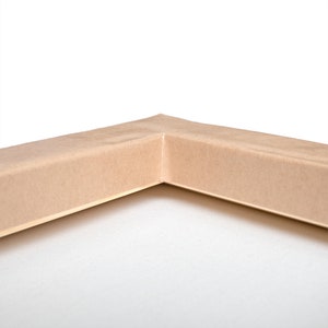 Puede incluir: Primer plano de la esquina de un marco de lienzo. El marco es de madera y est&aacute; pintado de color marr&oacute;n claro.