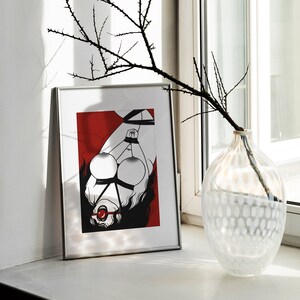 May include: A framed black and white illustration of a woman tied up with rope, wearing a red ball gag. The background is red. The frame is silver.