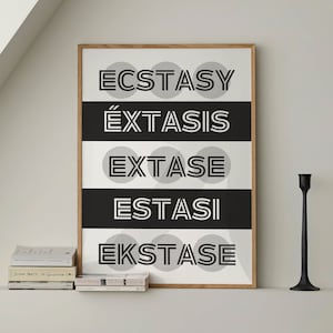 May include: A framed art print with the word "ECSTASY" in large, bold, white letters, set against a black and white striped background. The print is in a wooden frame and is displayed on a shelf with books and black candle holders.