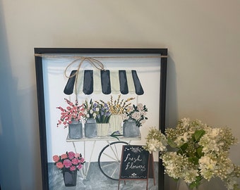 May include: A framed illustration of a flower cart with a black and white striped awning. The cart is filled with colorful flowers in jars. The sign on the cart reads "Fresh Flowers".