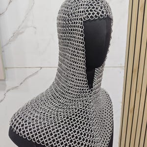 May include: A silver-colored chainmail coif constructed from numerous interlocking metal rings. The headpiece covers the top of the head and extends down to drape over the shoulders and upper chest, featuring a wide opening for the face.