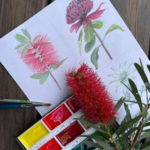 Pu&ograve; includere: Acquerello di fiori rossi e rosa con foglie verdi. Una tavolozza di acquerelli con vari colori &egrave; accanto al dipinto. Sono visibili anche dei pennelli.