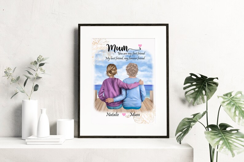 K&ouml;nnte beinhalten: Eine Aquarell-Illustration von zwei Frauen, die auf einem Steg sitzen und auf das Meer blicken. Die Frau im lila Pullover hat ihren Arm um die Frau im blauen Pullover gelegt. Der Text lautet "Mum Du bist meine erste Freundin Meine beste Freundin, meine Freundin f&uuml;r immer Natalie Mum".