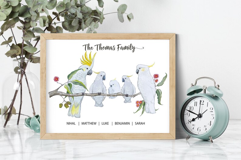 Pu&ograve; includere: Stampa incorniciata raffigurante una famiglia di cacatua bianchi su un ramo. L'illustrazione ad acquerello include il testo "The Thomas Family" e i nomi dei membri della famiglia. La cornice &egrave; marrone chiaro.