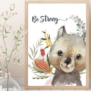 May include: A watercolor illustration of a cute wombat with a floral wreath around its head. The text "Be Strong" is written above the wombat. The background is white.