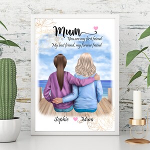 K&ouml;nnte beinhalten: Eine gerahmte Illustration von zwei Frauen, die auf einem Pier sitzen und auf das Meer blicken. Der Text lautet "Mum Du bist meine erste Freundin Meine beste Freundin, meine Freundin f&uuml;r immer" und ist mit "Sophie Mum" signiert.