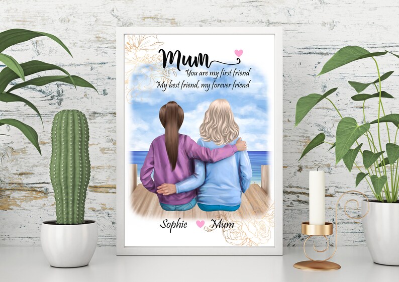 K&ouml;nnte beinhalten: Eine gerahmte Illustration von zwei Frauen, die auf einem Pier sitzen und auf das Meer blicken. Der Text lautet "Mum Du bist meine erste Freundin Meine beste Freundin, meine Freundin f&uuml;r immer" und ist mit "Sophie Mum" signiert.