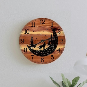 May include: A wooden clock with a crescent moon design featuring a wolf howling at the moon. The clock face has black Roman numerals and a black hand. The clock is hanging on a light grey wall.