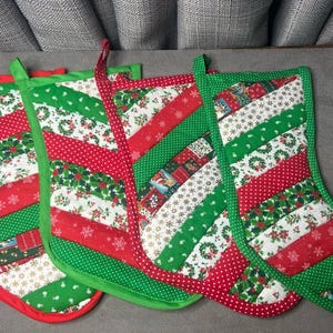 May include: Four Christmas stockings with red, green, and white patchwork designs. Each stocking has a different pattern, including polka dots, snowflakes, and holiday imagery. The stockings are trimmed with red and green fabric and have loops for hanging.