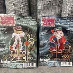 May include: Two Christmas cross-stitch kits from the Collector's Series. One features St. Nick with a lantern, the other a Santa with a Christmas tree. Finished size is 7.6 cm x 12.1 cm.