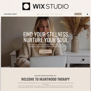 Op de afbeelding: Website-ontwerp voor Heartwood Therapy, met het Wix Studio-logo bovenaan. De pagina toont een vrouw die een laptop gebruikt. De hoofdtekst luidt "Find Your Stillness. Nurture Your Soul." De site heeft een neutraal kleurenpalet en een call-to-action-knop.